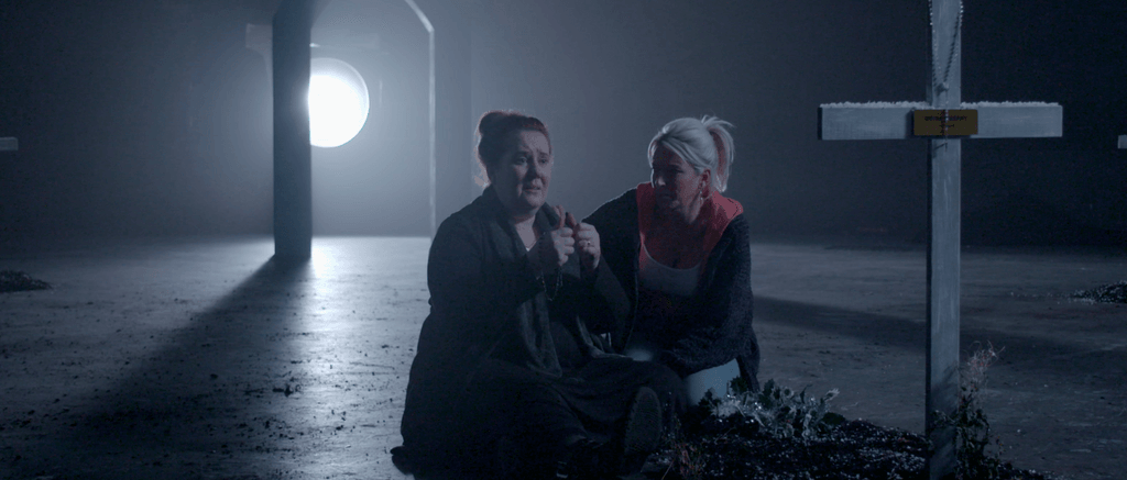 Two women praying at a graveside